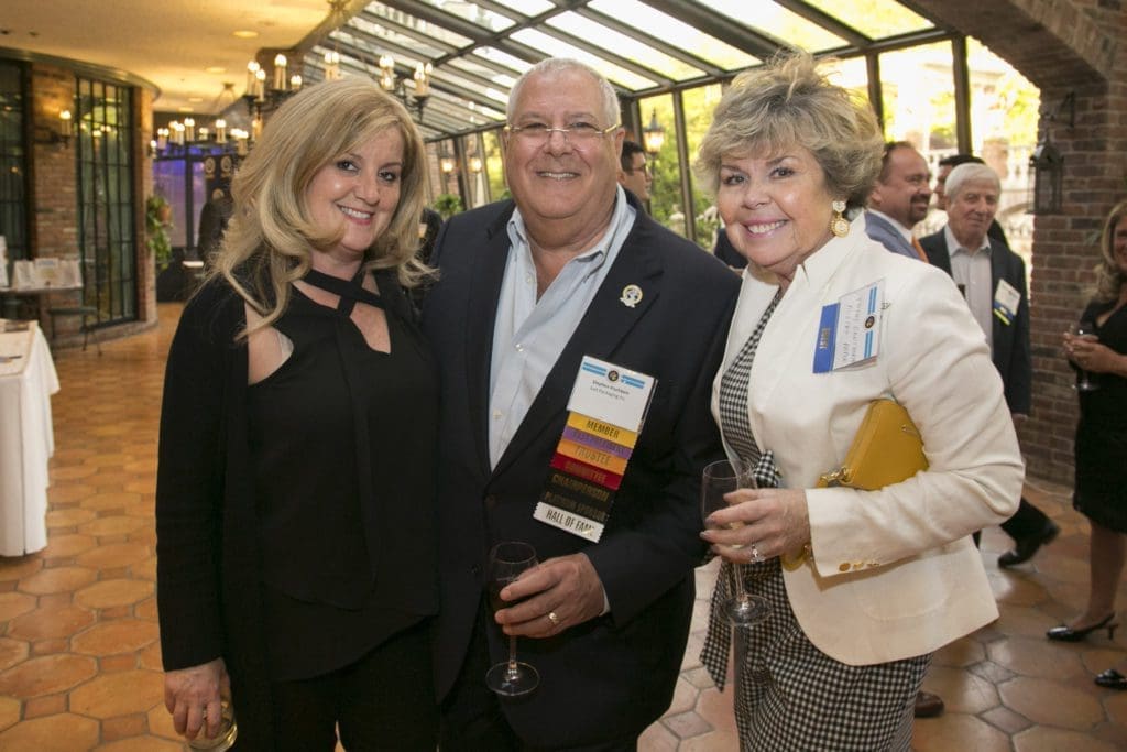 Three attendees smiling under glass ceiling