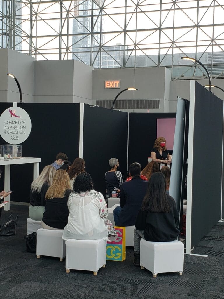 Audience listening to speaker at cosmetics booth