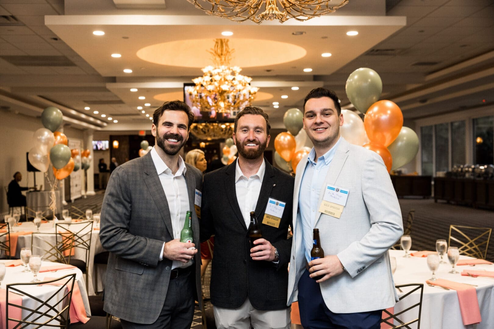 Three men in suits holding drinks at an event.