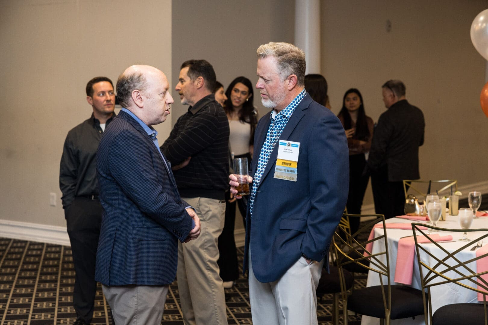 Two men in suits are talking at a business event.