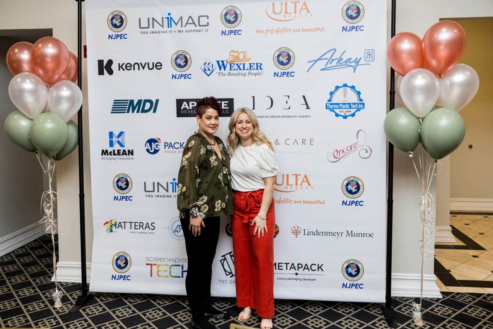 Two women posing in front of a step-and-repeat.