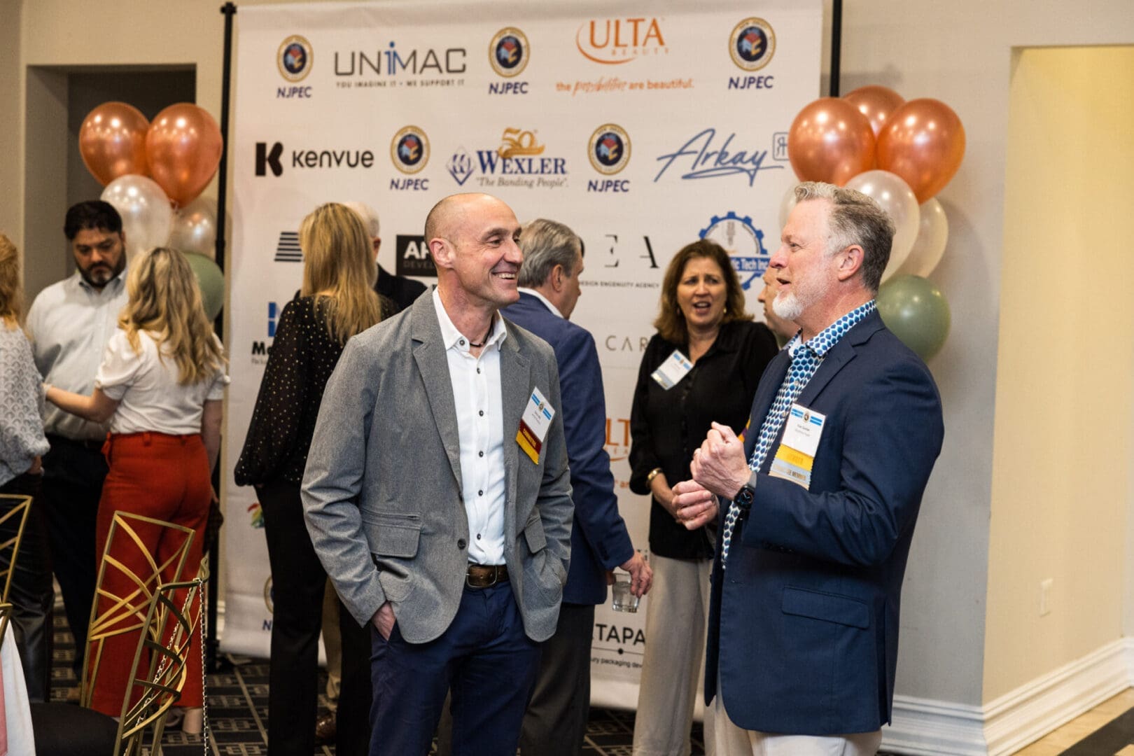 Two men in suits talking at a business event.