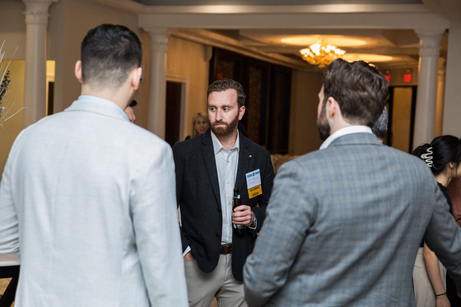 Three men in suits talking at a conference.