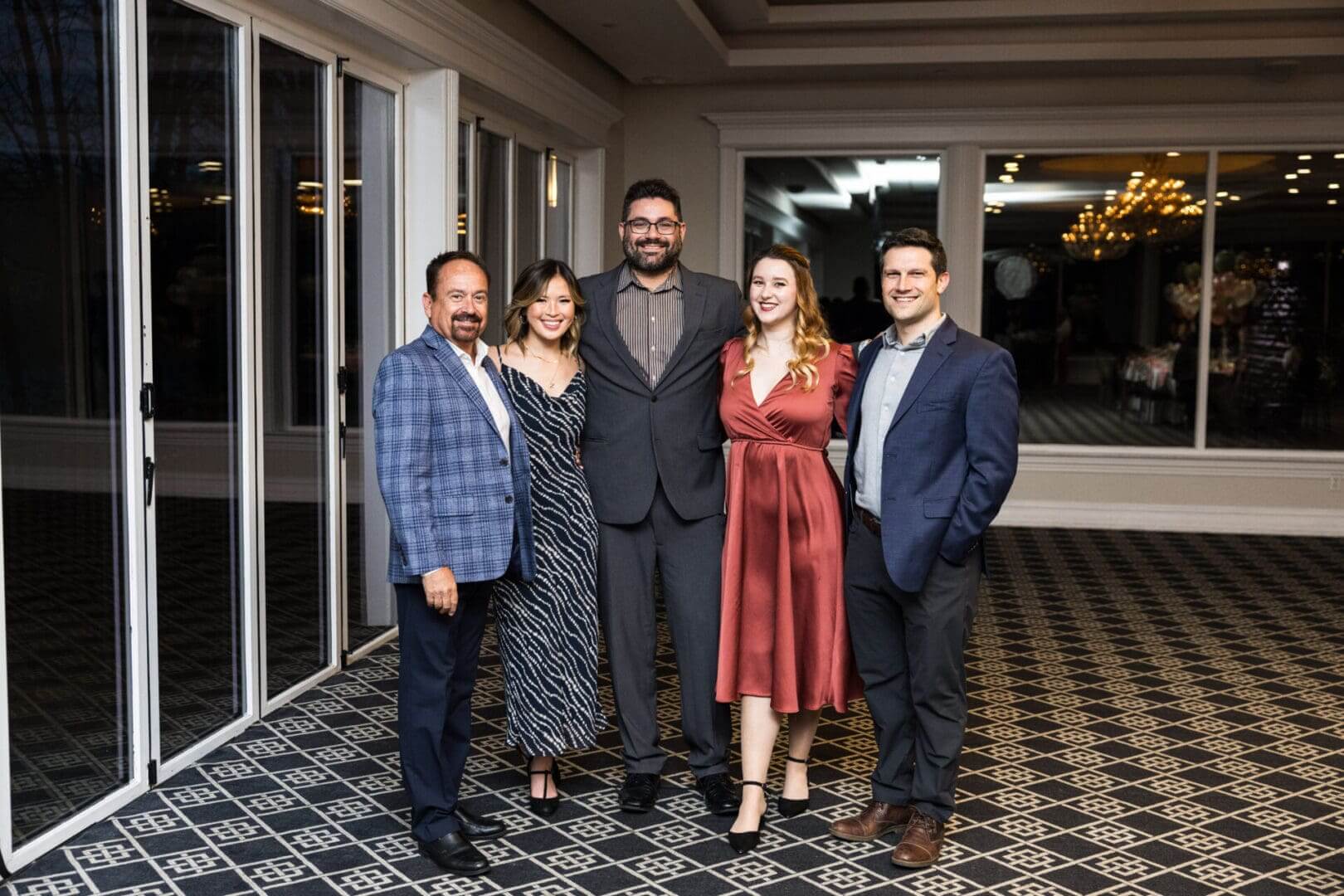 Five people posing for a photo at a wedding.