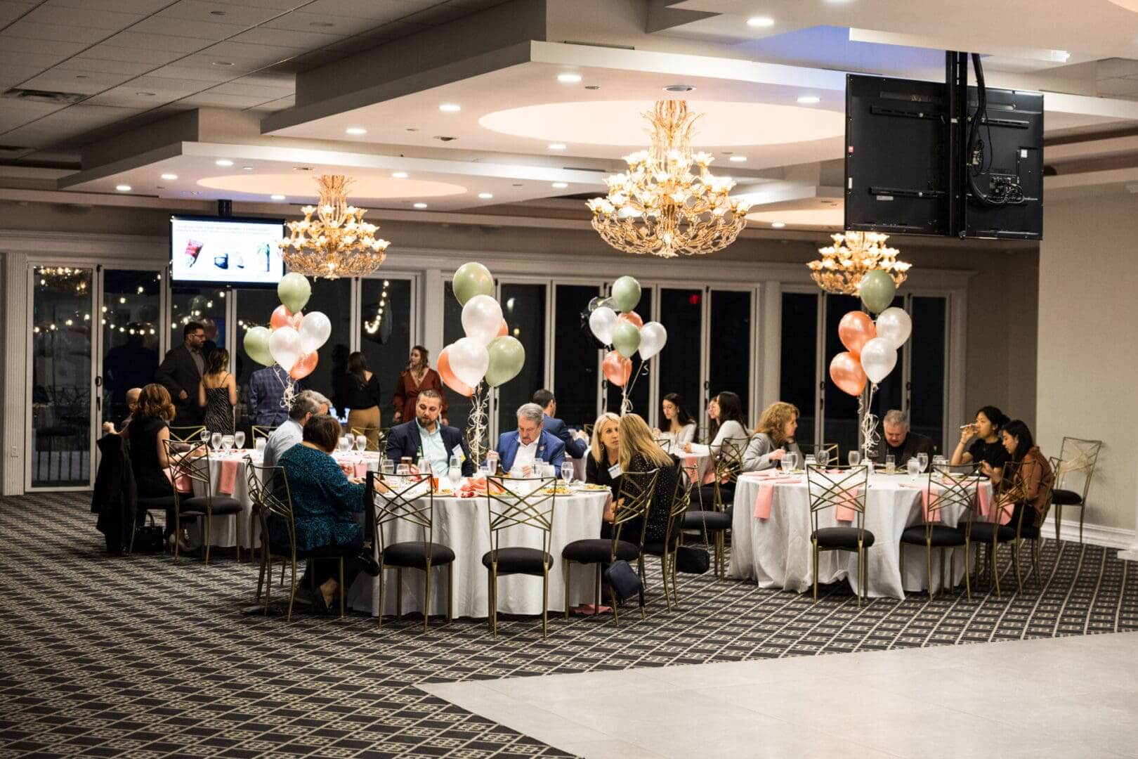 A group of people are sitting at tables in a decorated hall.