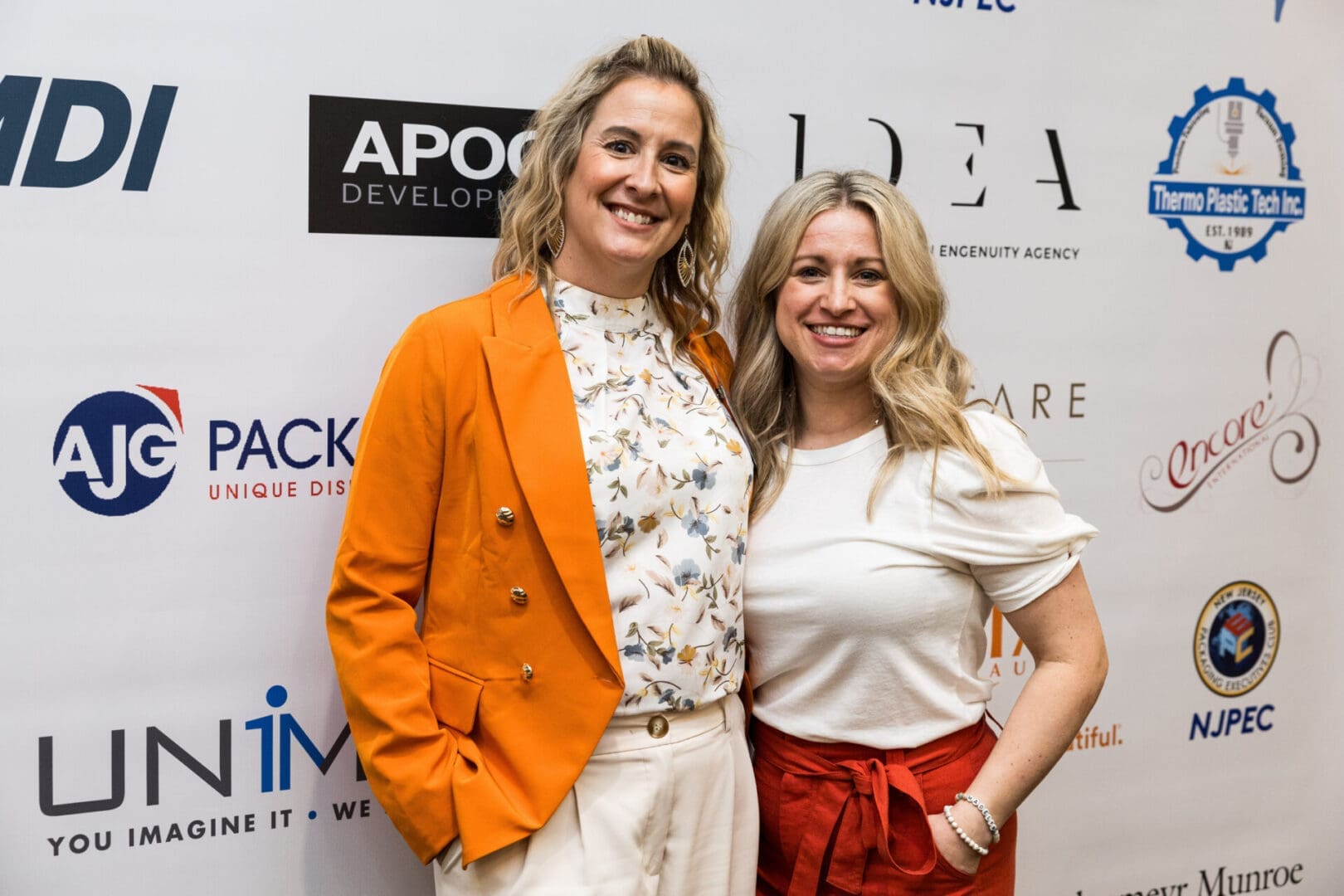 Two women in business attire posing together at an event.
