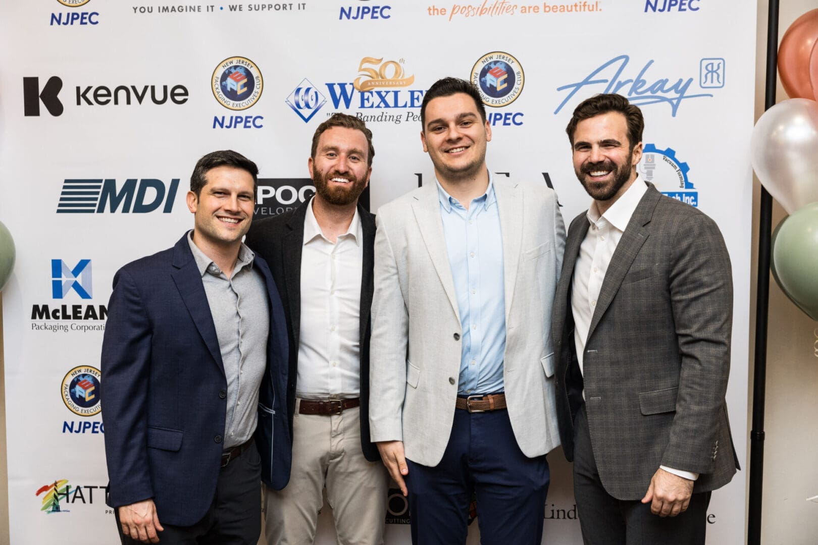 Four men in suits posing for a photo at an event.