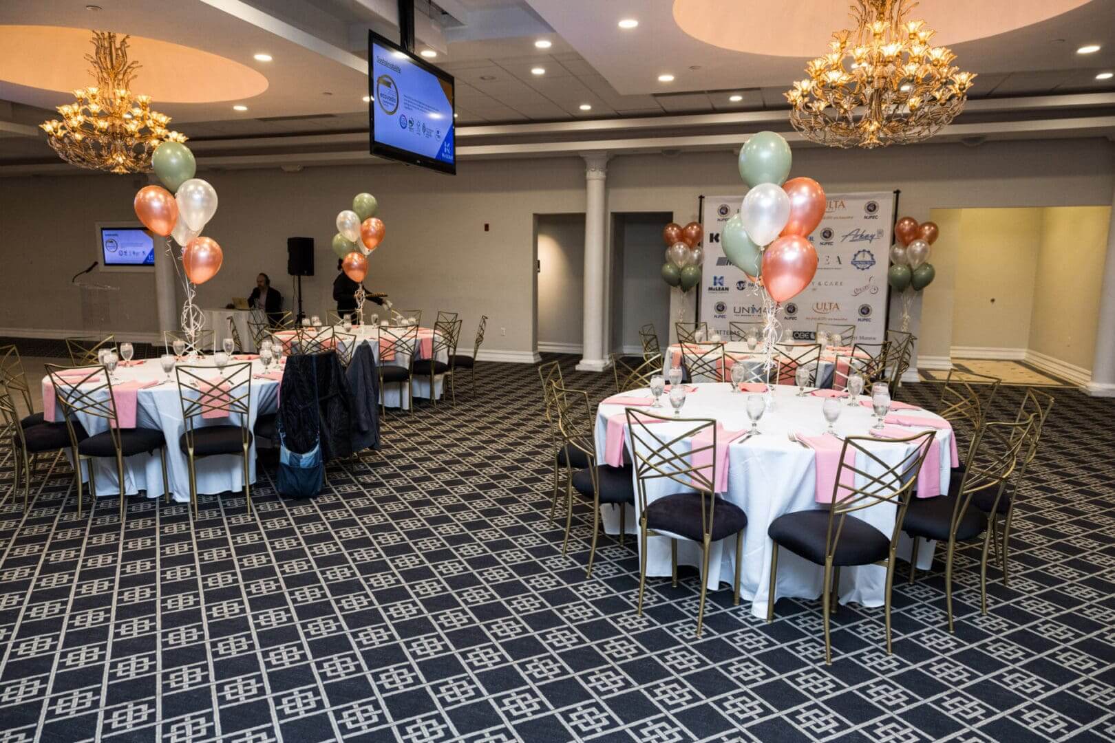 A decorated ballroom with round tables and chairs.