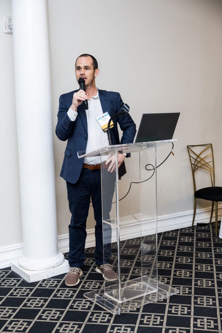 A man in a suit is speaking into a microphone.