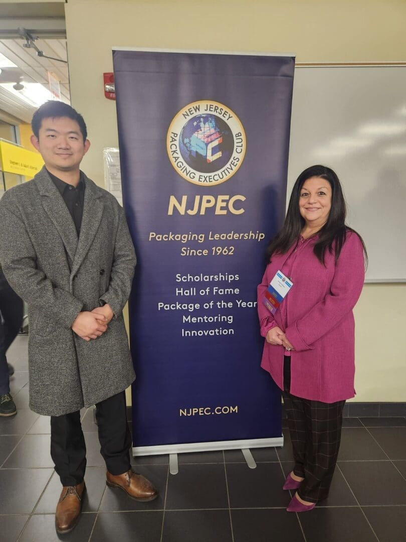 Two people beside NJPEC banner display.