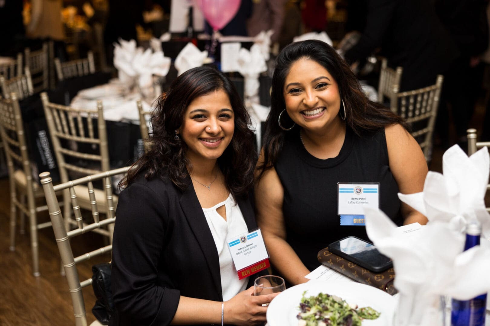 Two smiling women at a dining table.