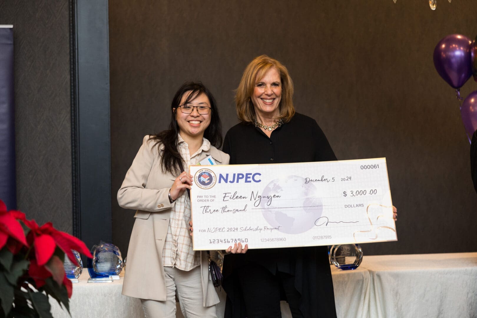 Women holding a large scholarship check together.