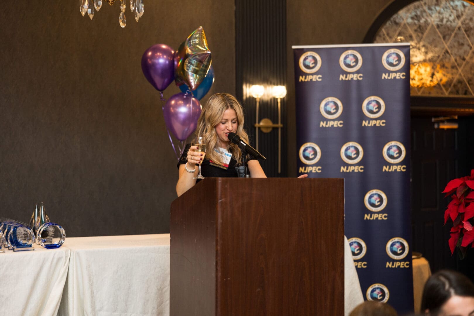 Woman speaking at event with balloons.