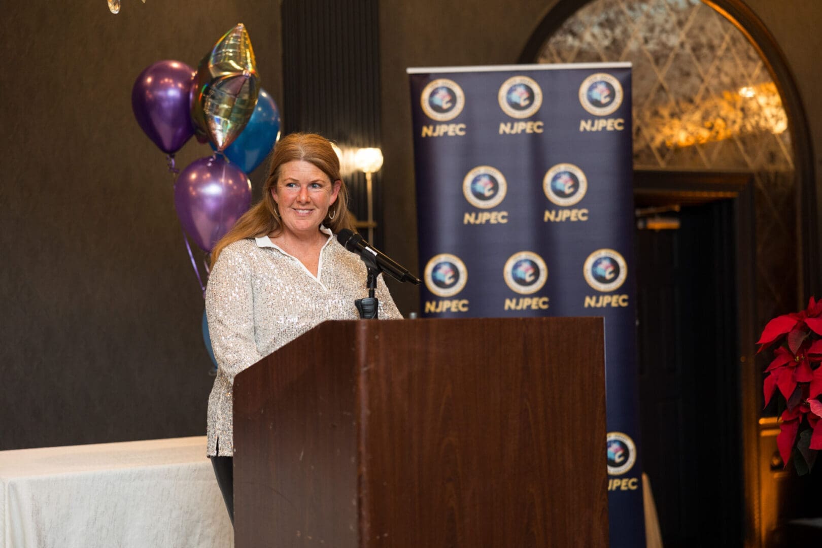 Woman speaking at a podium with decorations.