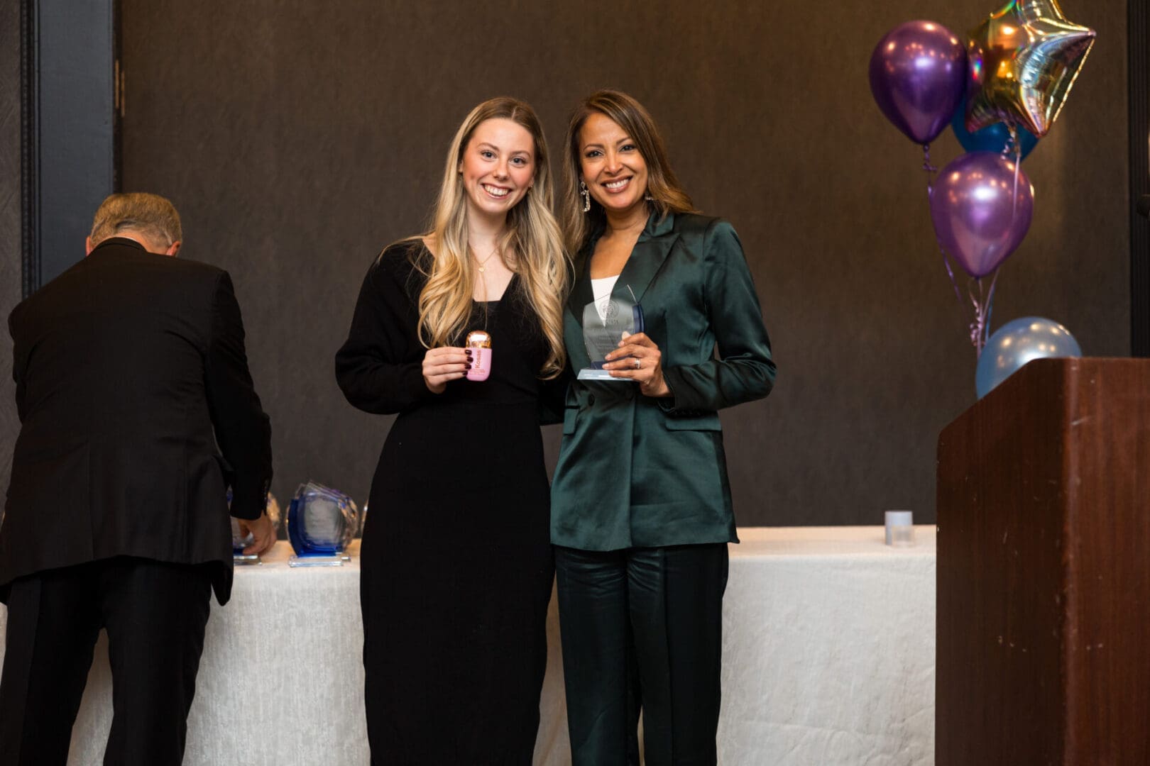 Two women holding awards at an event.