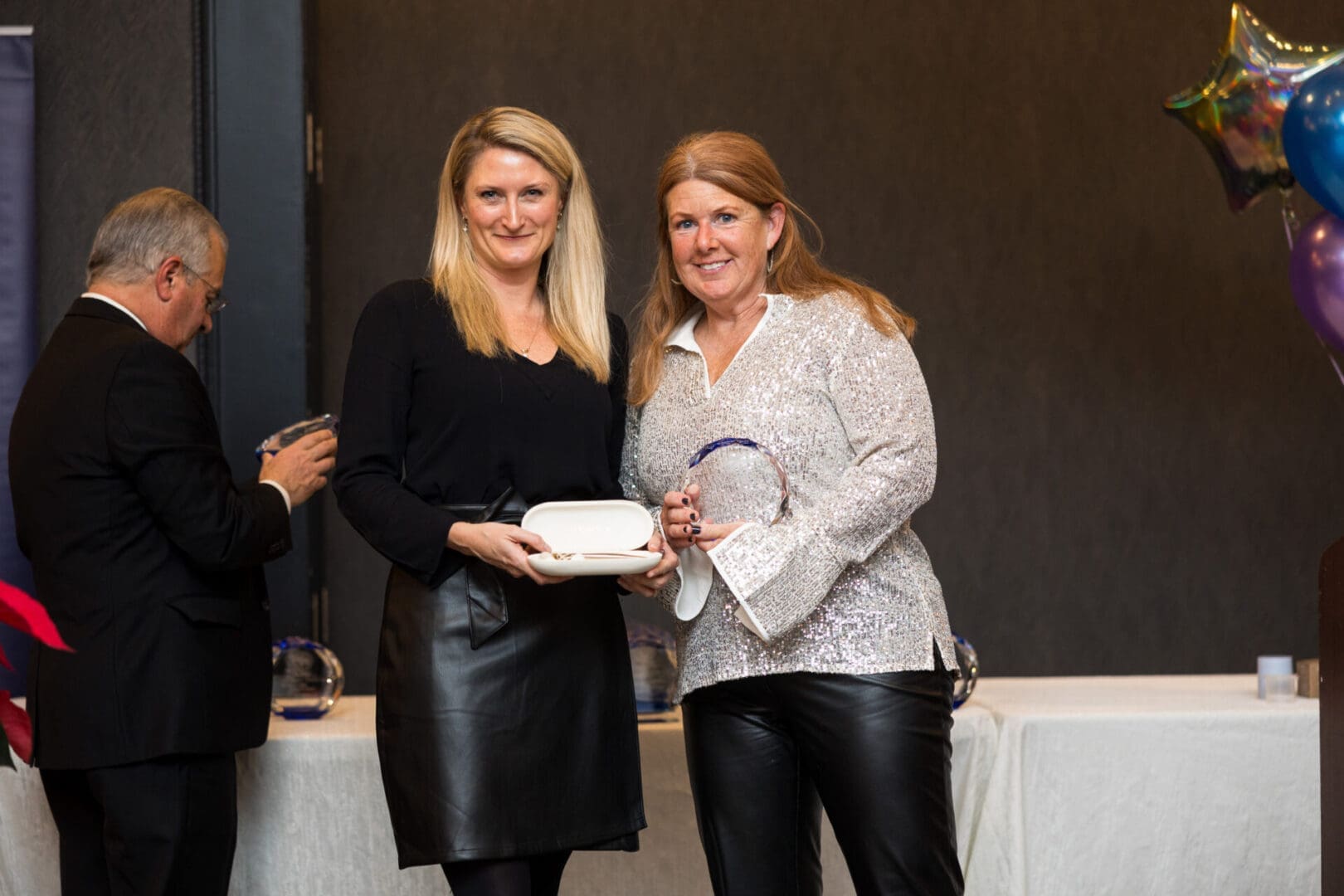 Two women holding awards at an event.