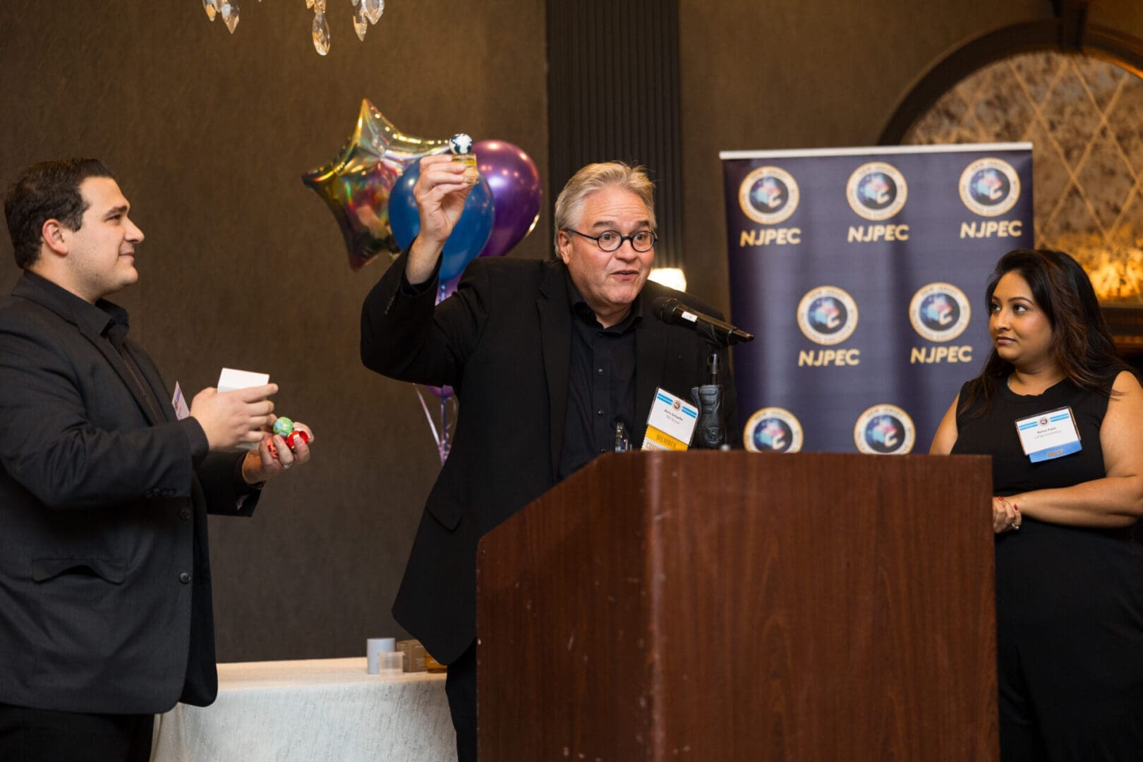 Conference speakers presenting with props at podium.