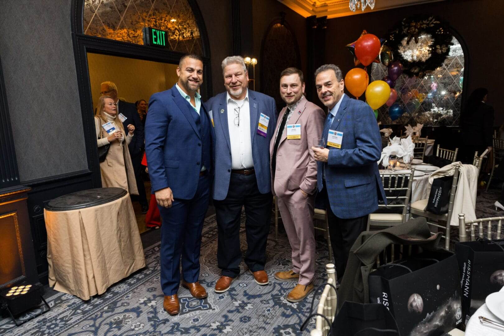 Four men posing at a social event.