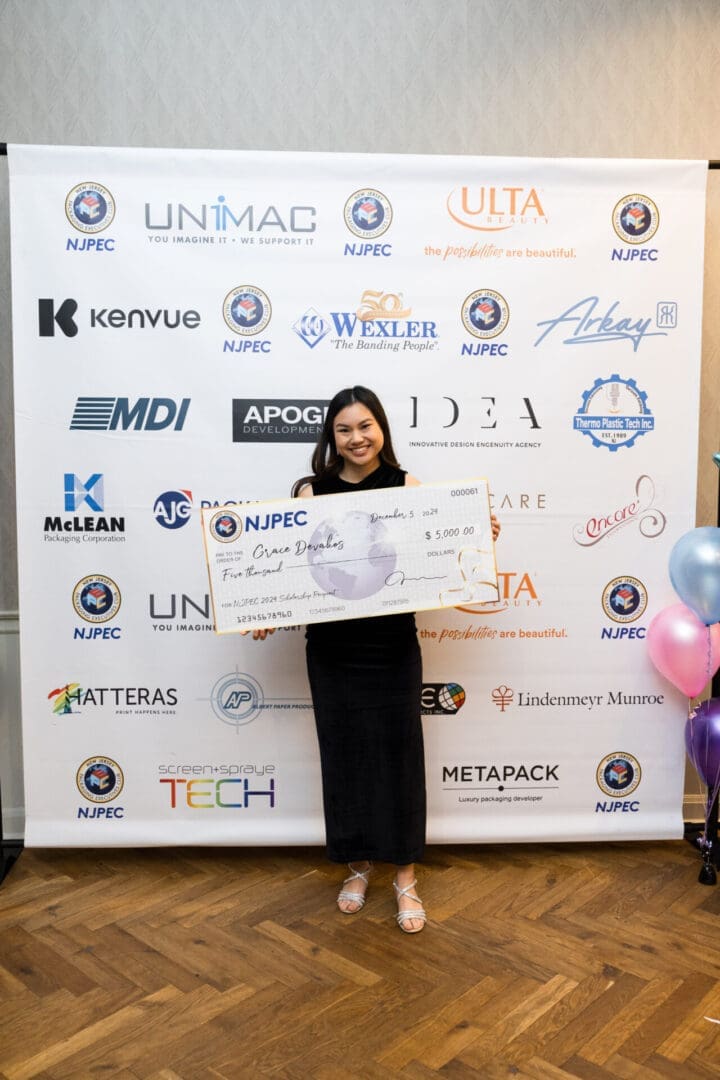 Woman holding large scholarship check at event.
