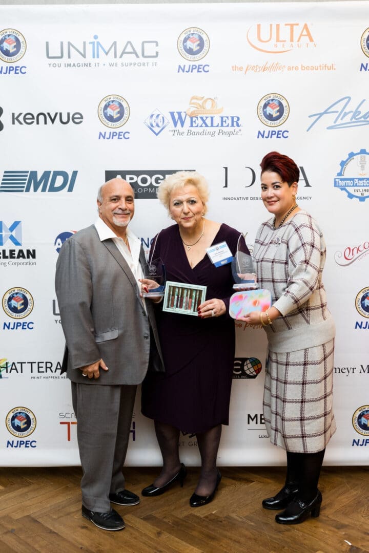 Three people holding awards at an event.