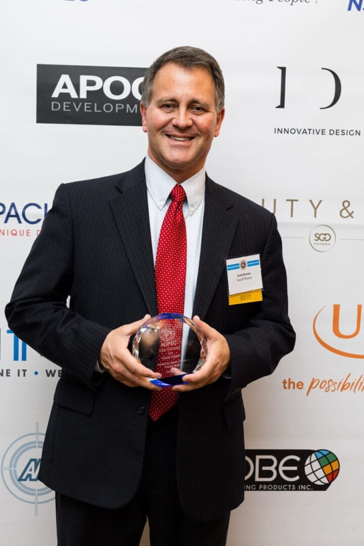 Man holding award at event backdrop.