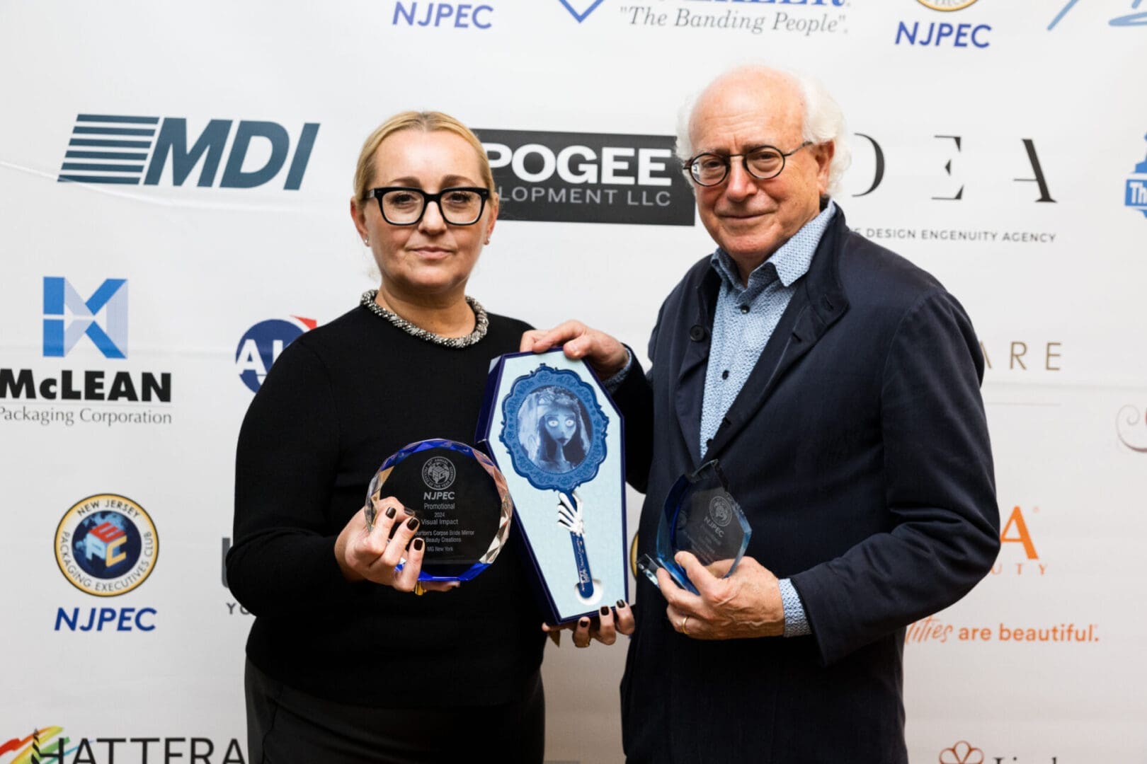 Two individuals holding awards together.
