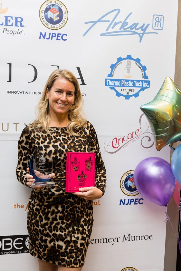 Woman holding award and pink book.