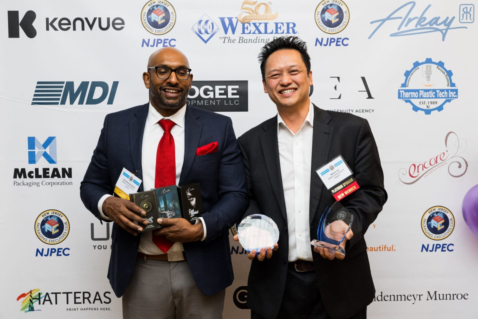 Two men holding awards and boxes.