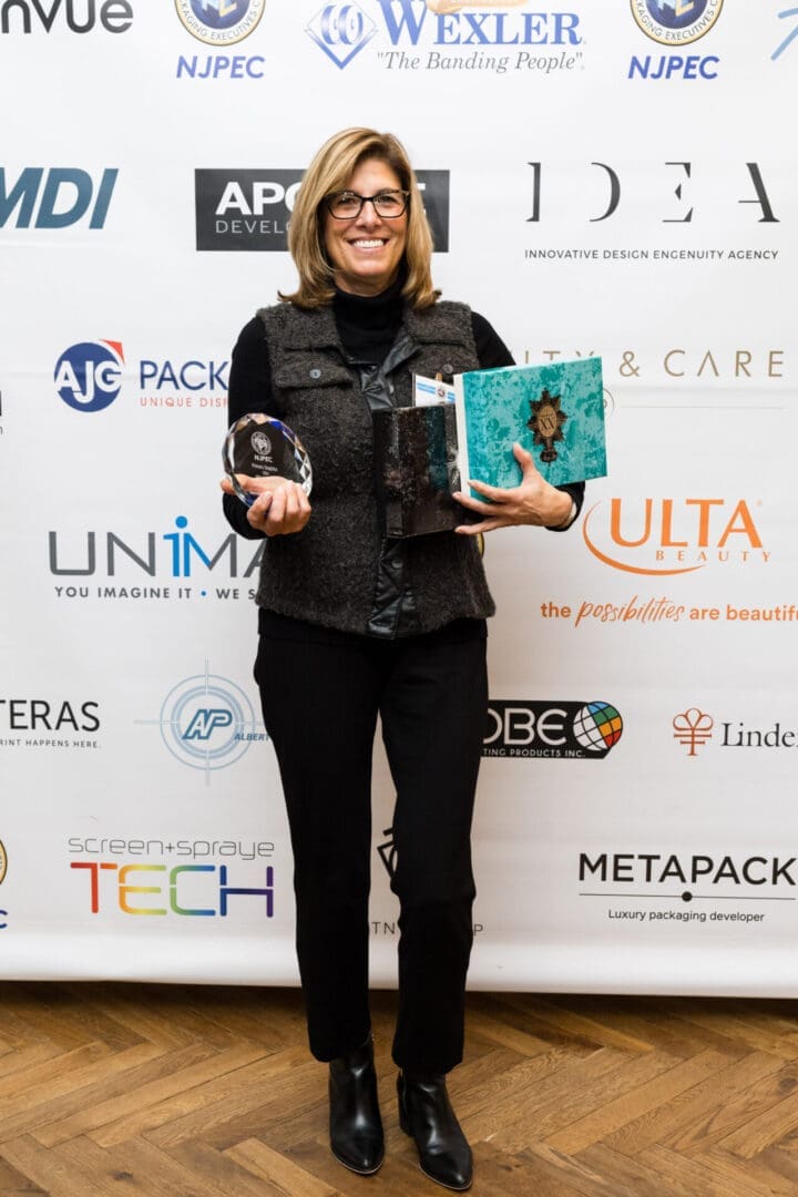 Woman holding awards and a binder at event.