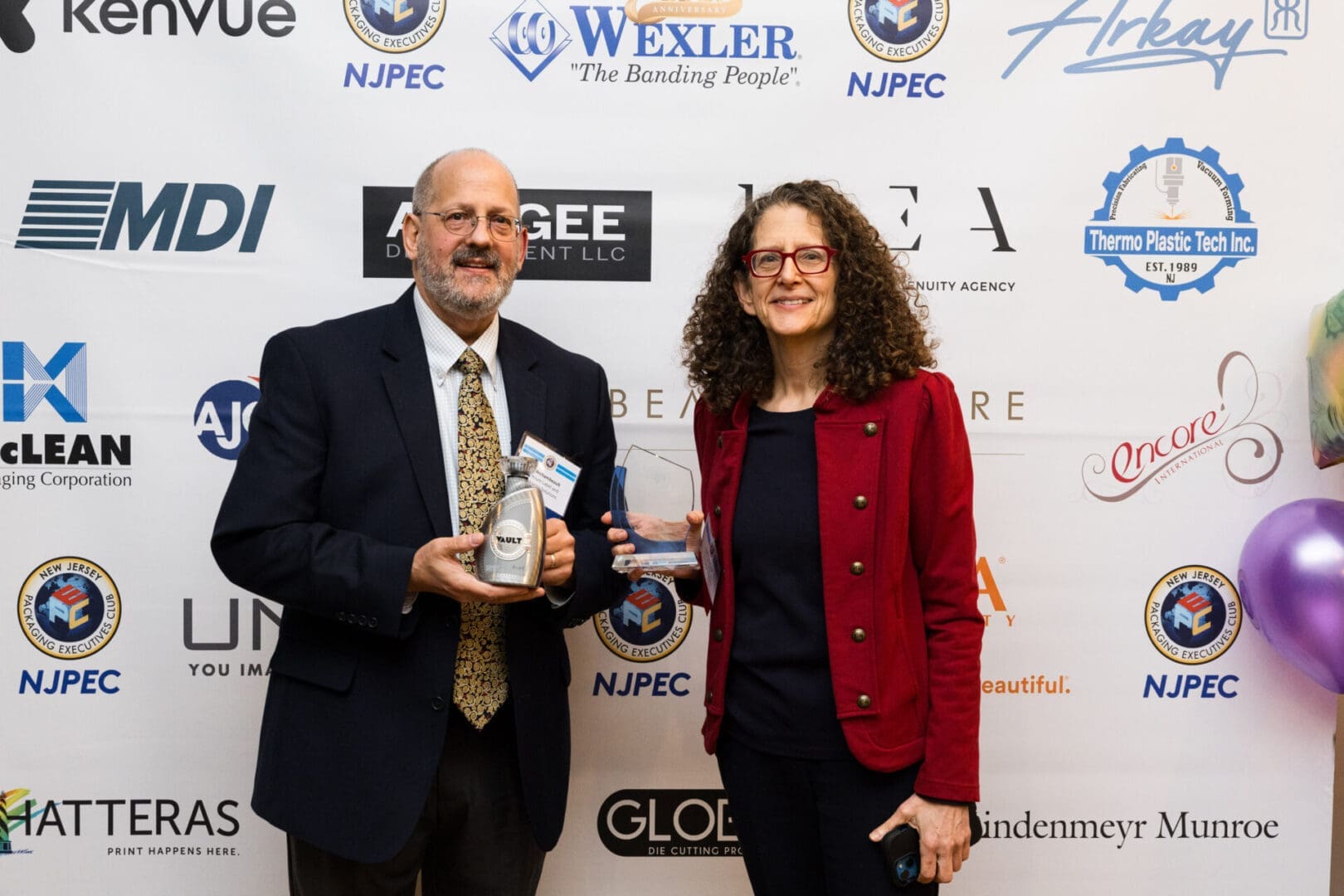 Two people holding awards at an event.