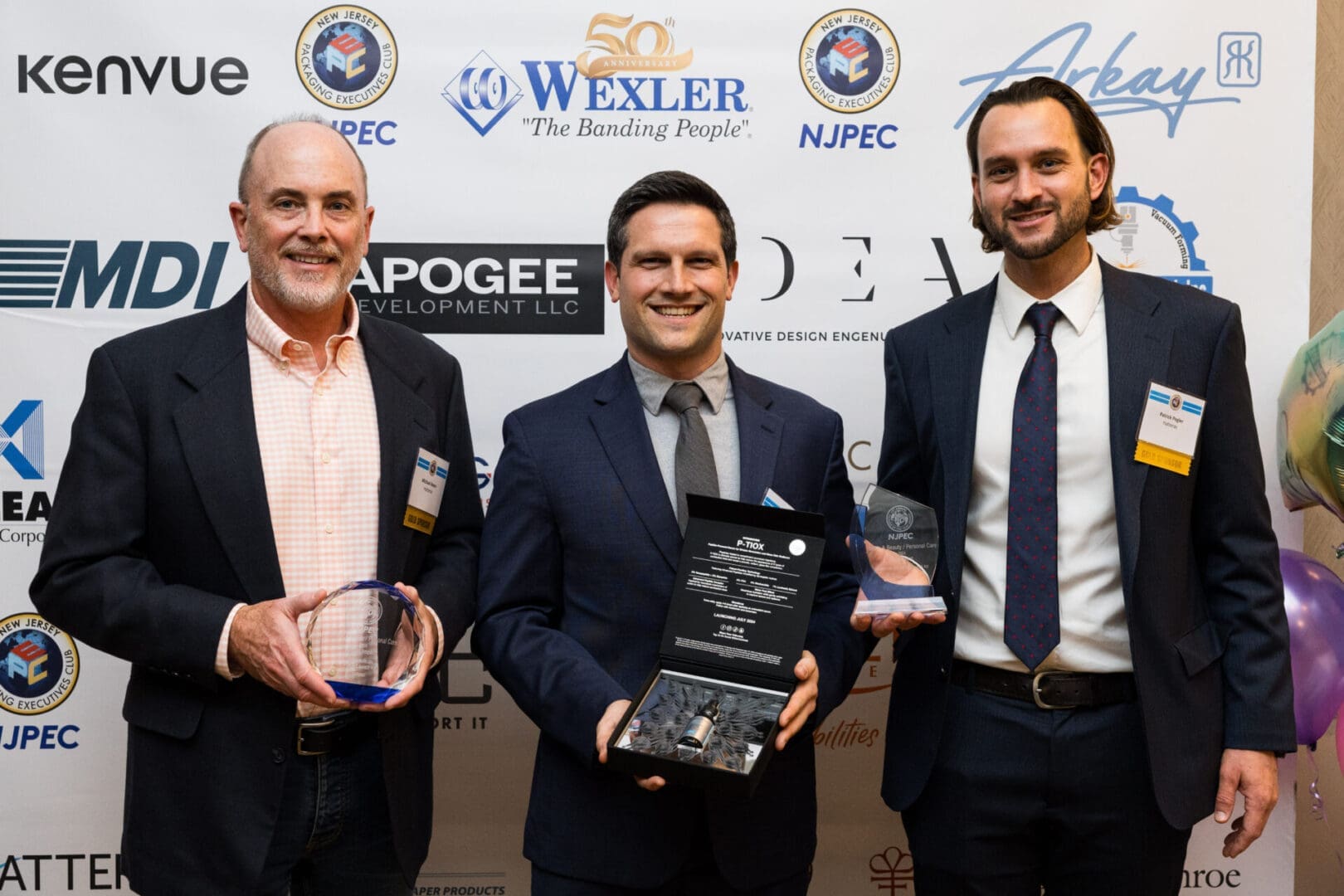 Three men holding awards at an event.