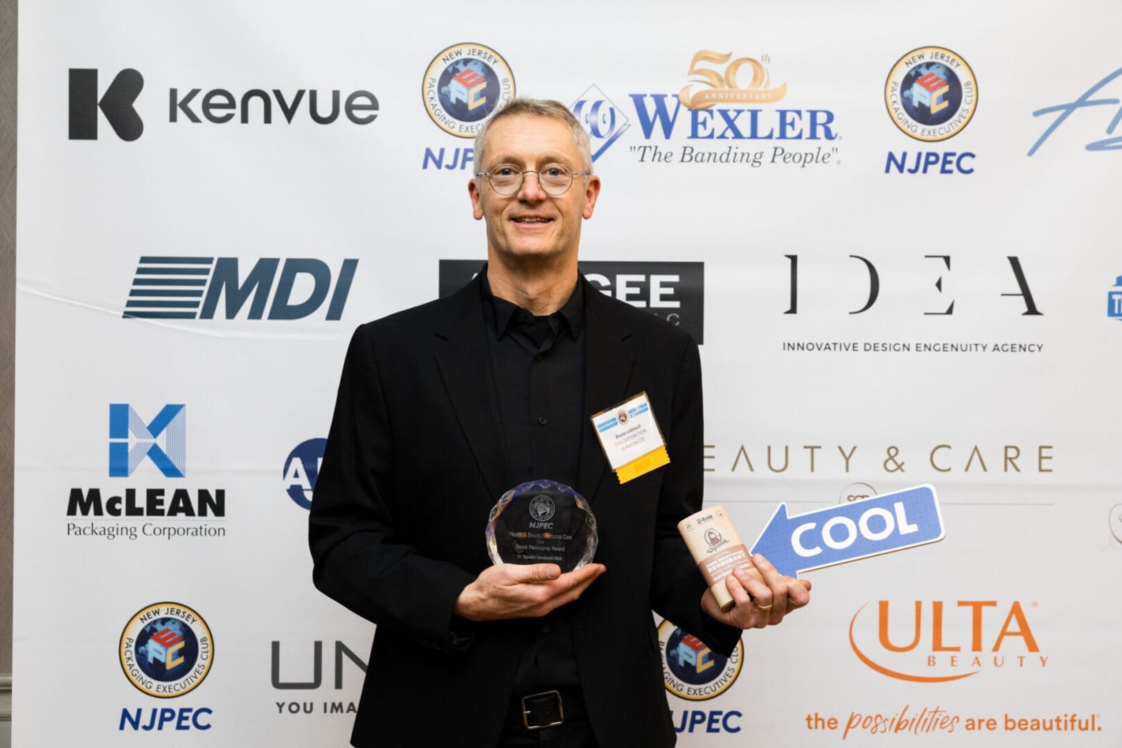 Man holding awards at a promotional event.