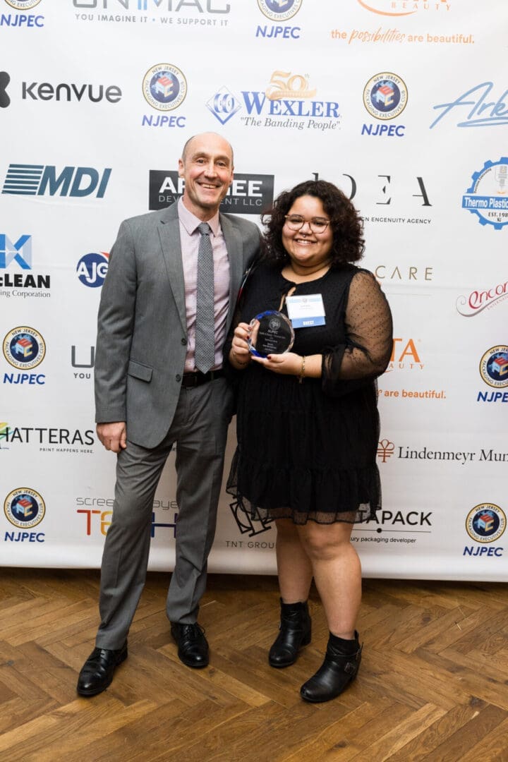 Two individuals pose with an award.