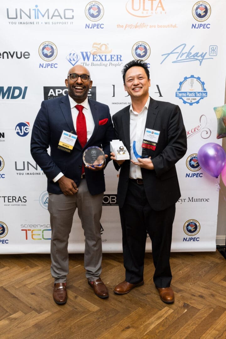 Two men holding awards at event.