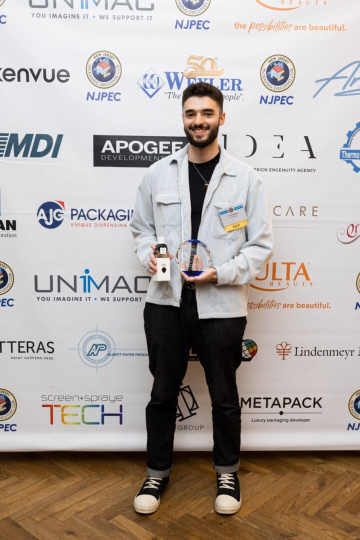 Man holding award in front of sponsor backdrop.