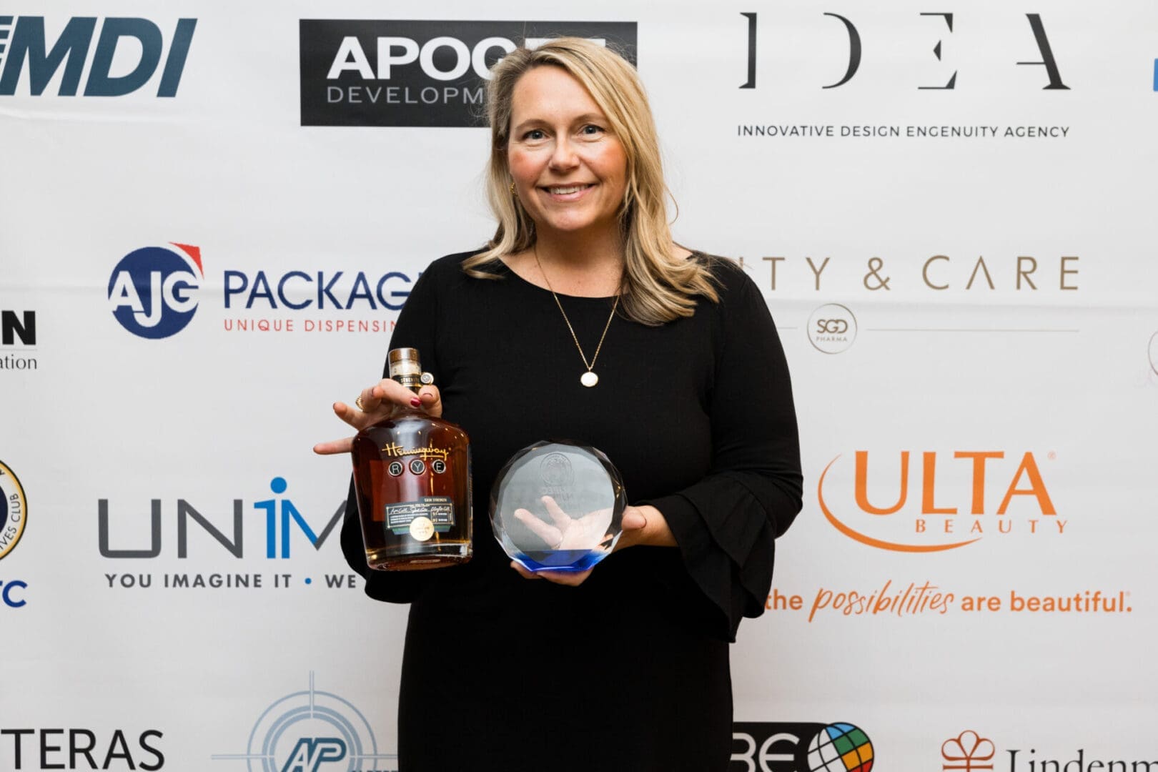 Woman holding award and whiskey bottle.