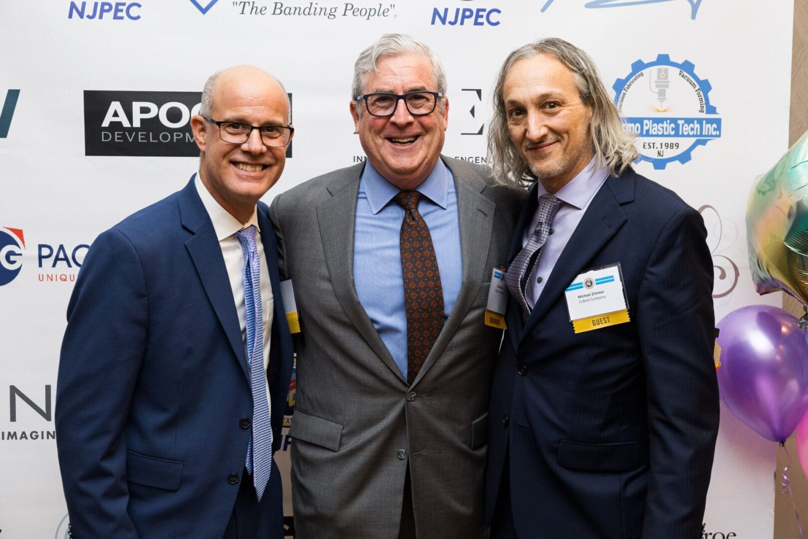 Three smiling men at an event.