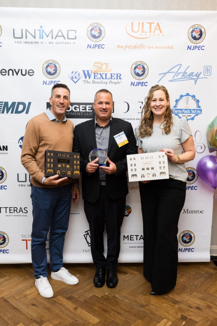Three people holding awards at an event.