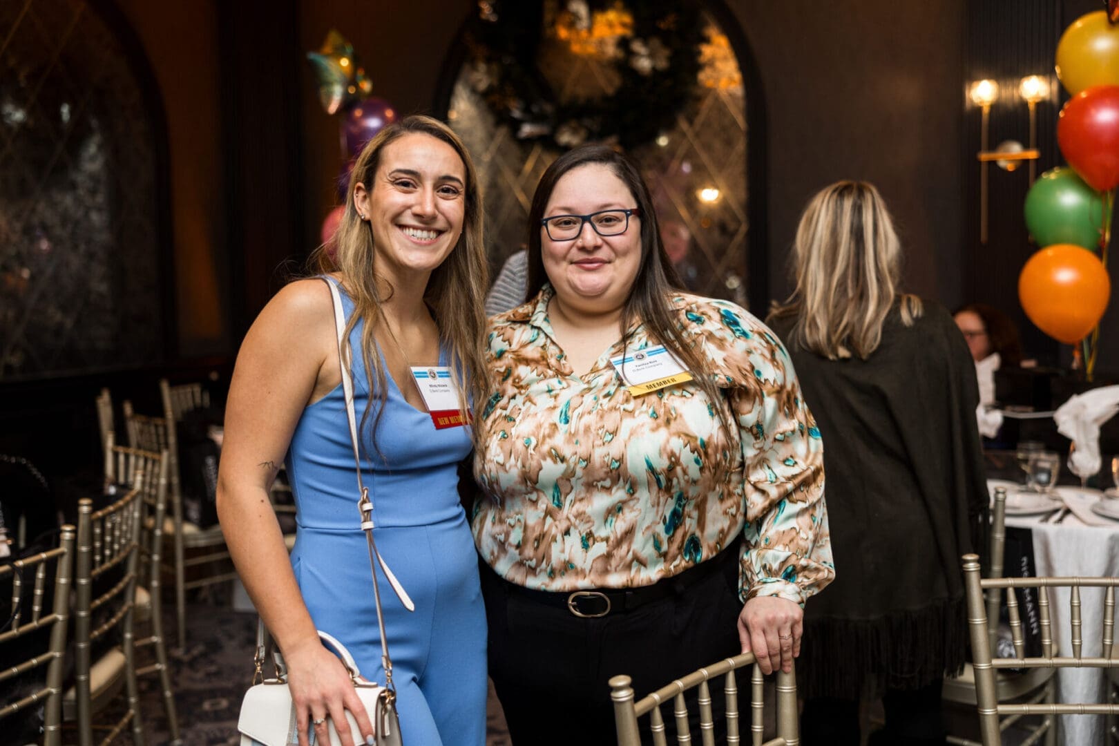 Two women smiling at a festive event.