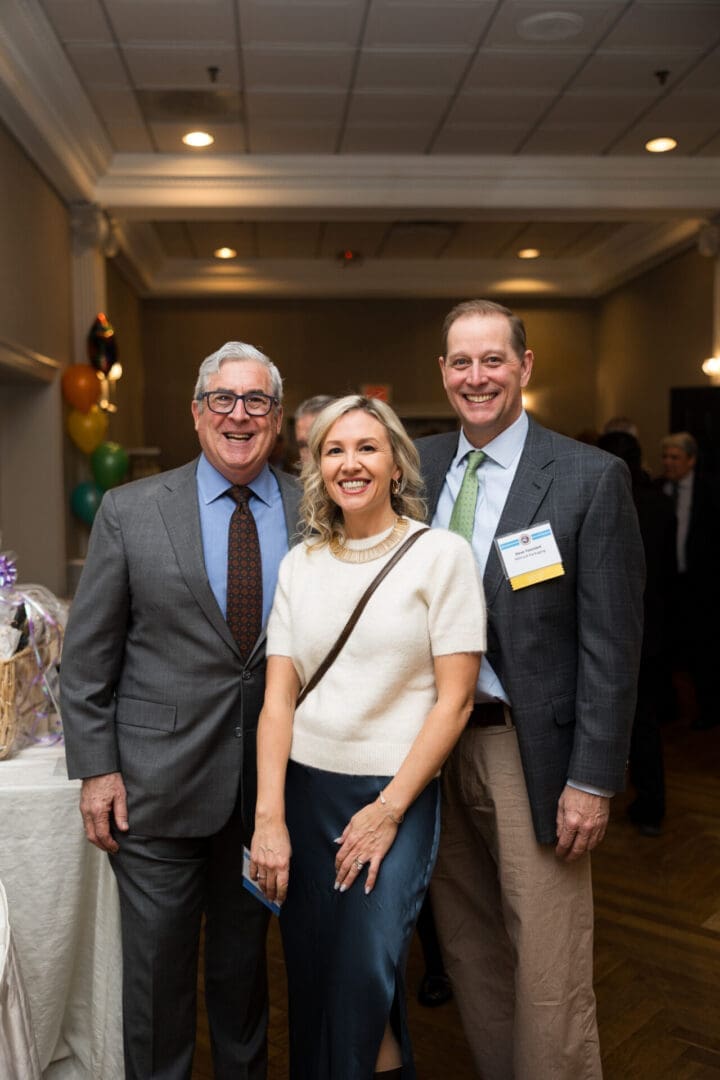 Three people smiling at a social event.
