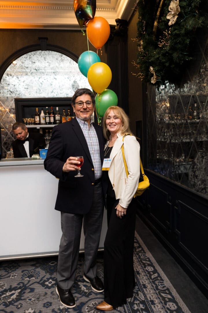 Couple posing with drinks and balloons.