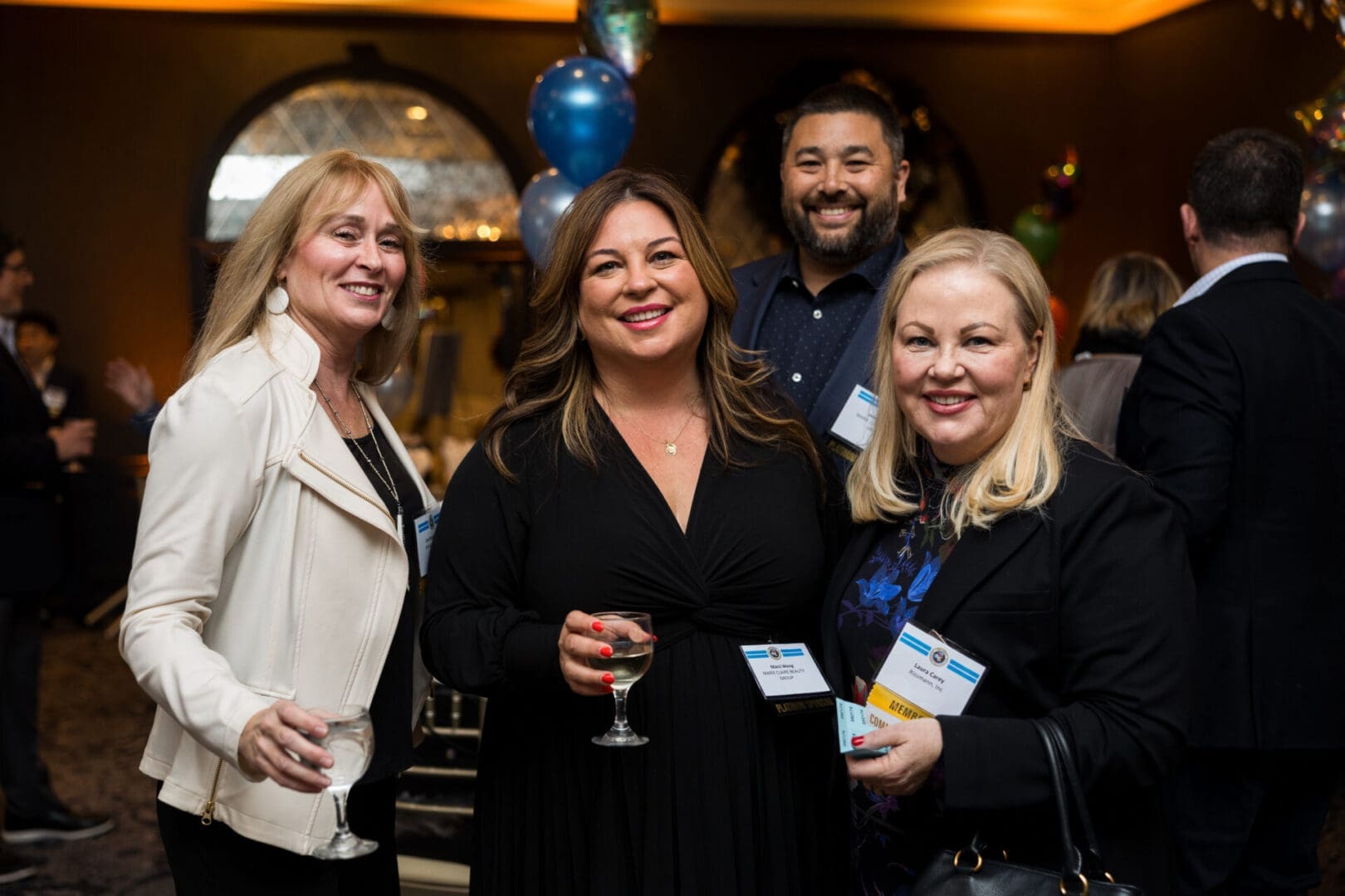 Four people smiling at a social event.