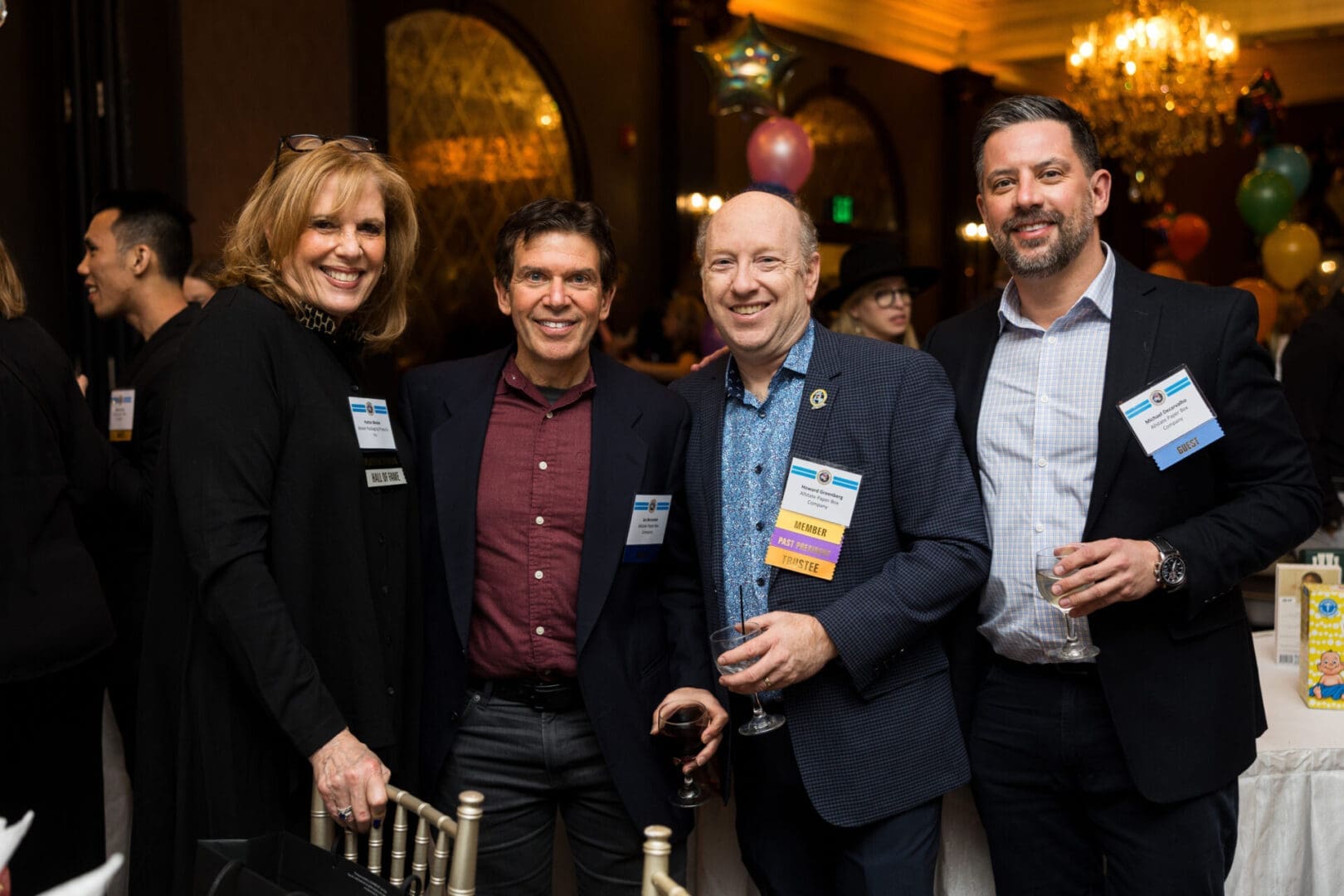 Four people smiling at a social event.