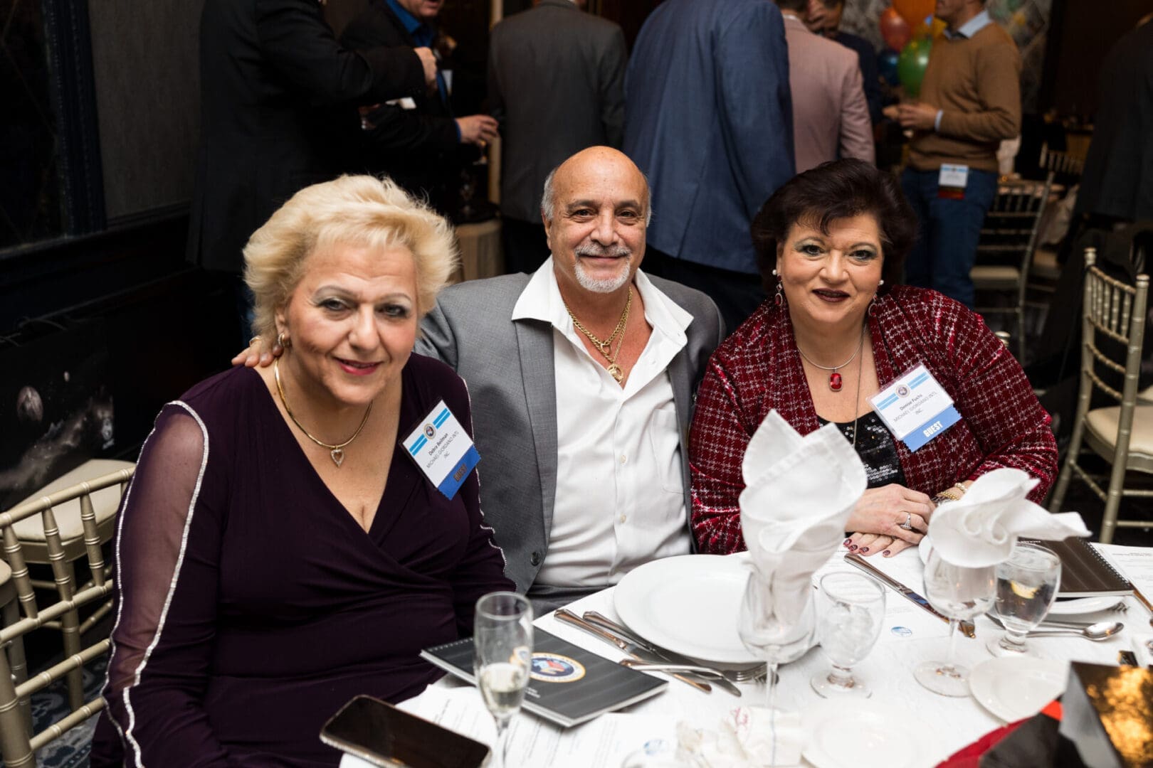 Three people smiling at a dinner table.