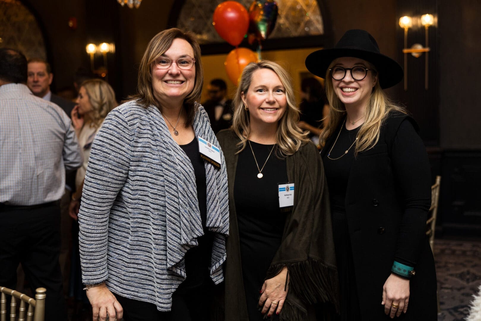 Three women smiling at an event.