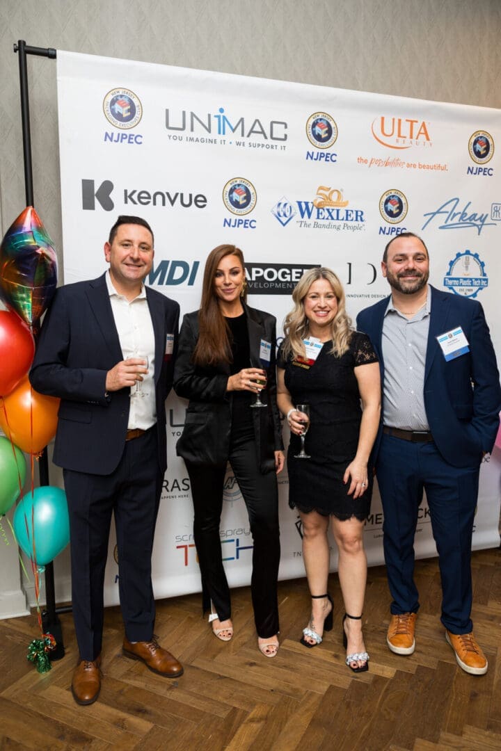 Four people posing at an event backdrop.