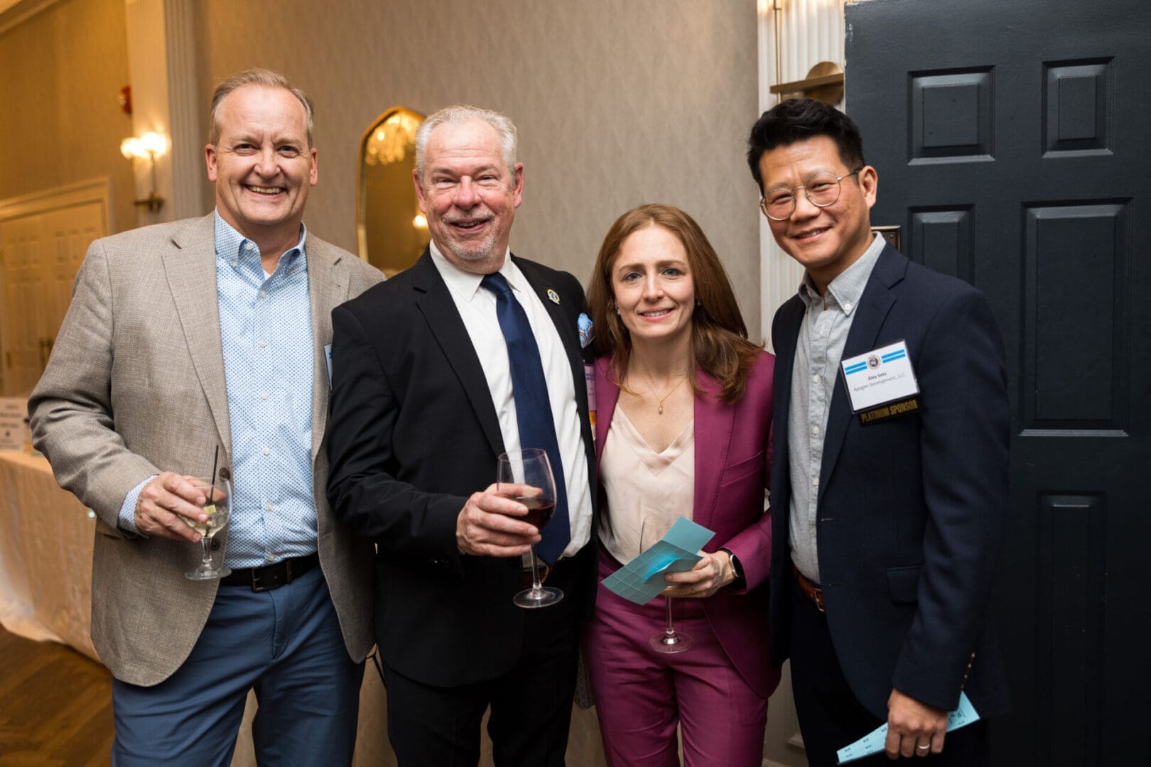 Four people smiling at a social event.