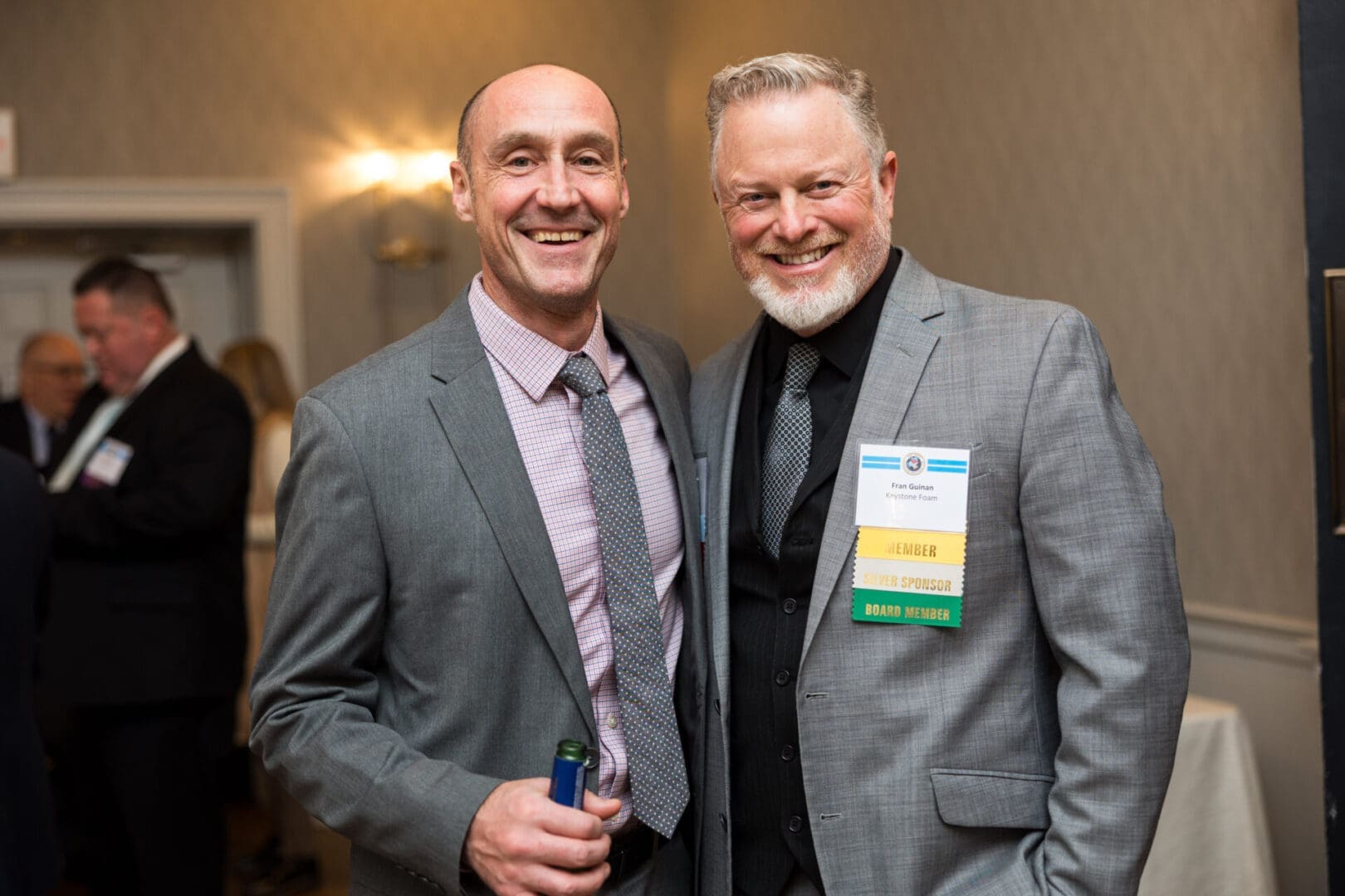 Two men smiling at a formal event.