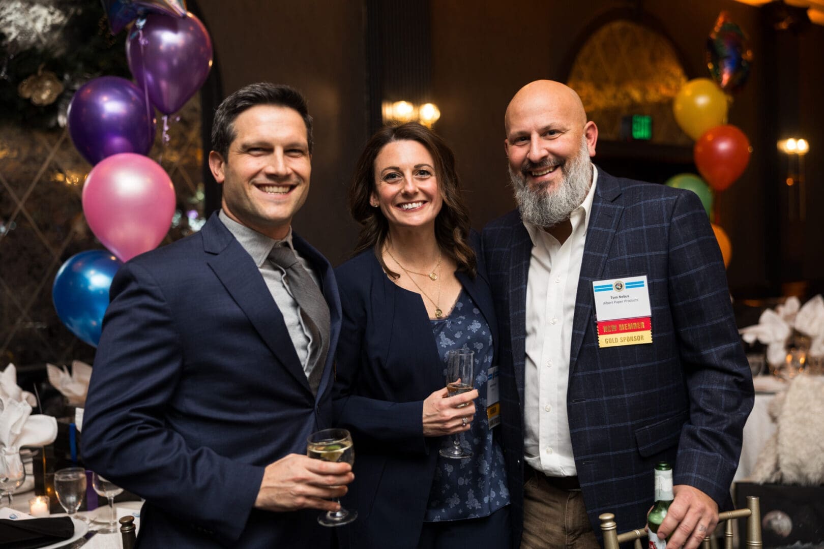 Three people smiling at a celebration event.