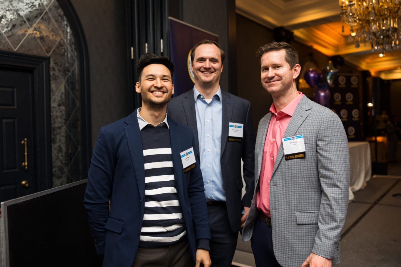 Three men smiling at a networking event.